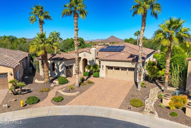 mediterranean / spanish home featuring a garage, a mountain view, and solar panels