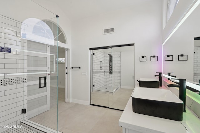 full bath featuring a towering ceiling, a shower stall, visible vents, and a sink