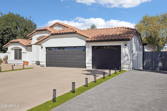 mediterranean / spanish-style home featuring a garage, driveway, and a tiled roof