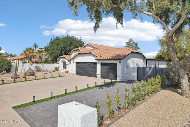 exterior space featuring a garage, driveway, a tiled roof, fence, and stucco siding