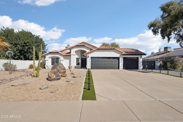 mediterranean / spanish-style home with a tile roof, stucco siding, concrete driveway, fence, and a garage