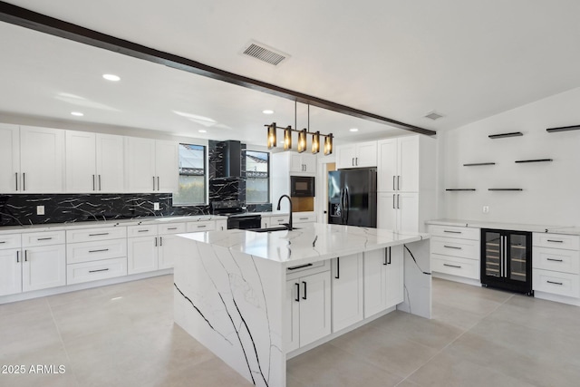 kitchen featuring visible vents, white cabinets, an island with sink, wine cooler, and black appliances