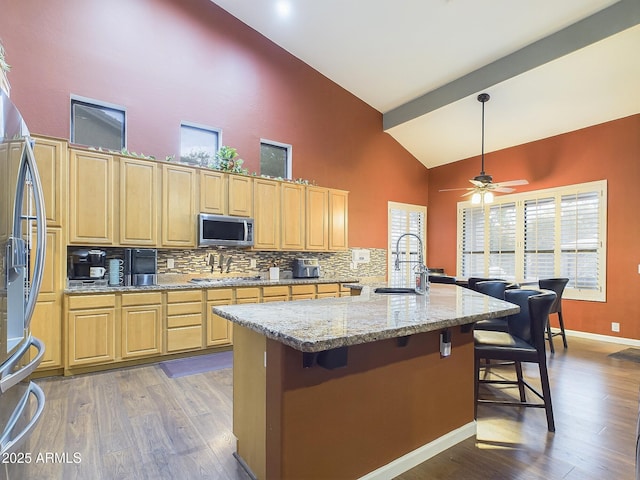 kitchen with a breakfast bar, sink, tasteful backsplash, appliances with stainless steel finishes, and light stone countertops