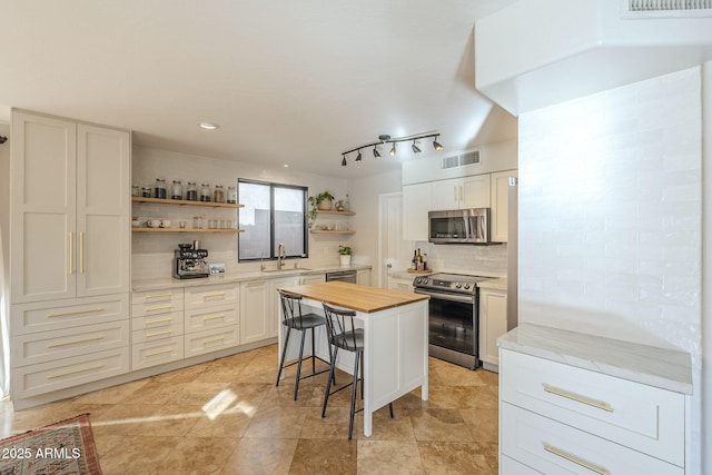 kitchen featuring stainless steel appliances, a center island, a breakfast bar, sink, and white cabinetry