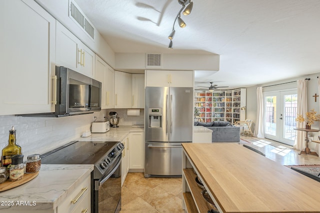 kitchen featuring white cabinets, stainless steel appliances, french doors, and tasteful backsplash