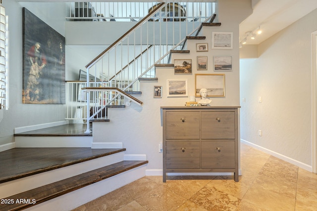 stairs featuring a towering ceiling and rail lighting