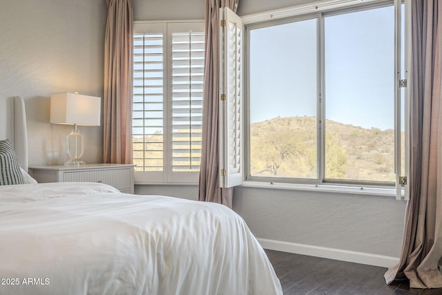 bedroom with a mountain view, dark hardwood / wood-style flooring, and multiple windows