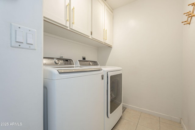 washroom featuring cabinets, light tile patterned flooring, and washer and clothes dryer