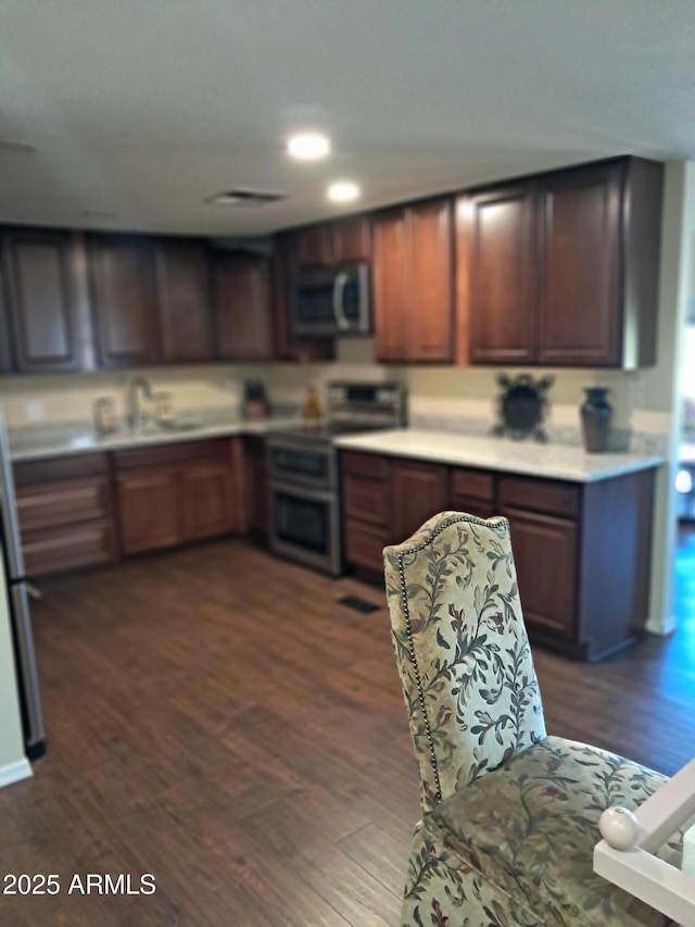 kitchen featuring dark wood-type flooring, electric stove, dark brown cabinets, and sink