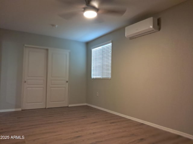 unfurnished bedroom featuring ceiling fan, a wall mounted air conditioner, a closet, and wood-type flooring