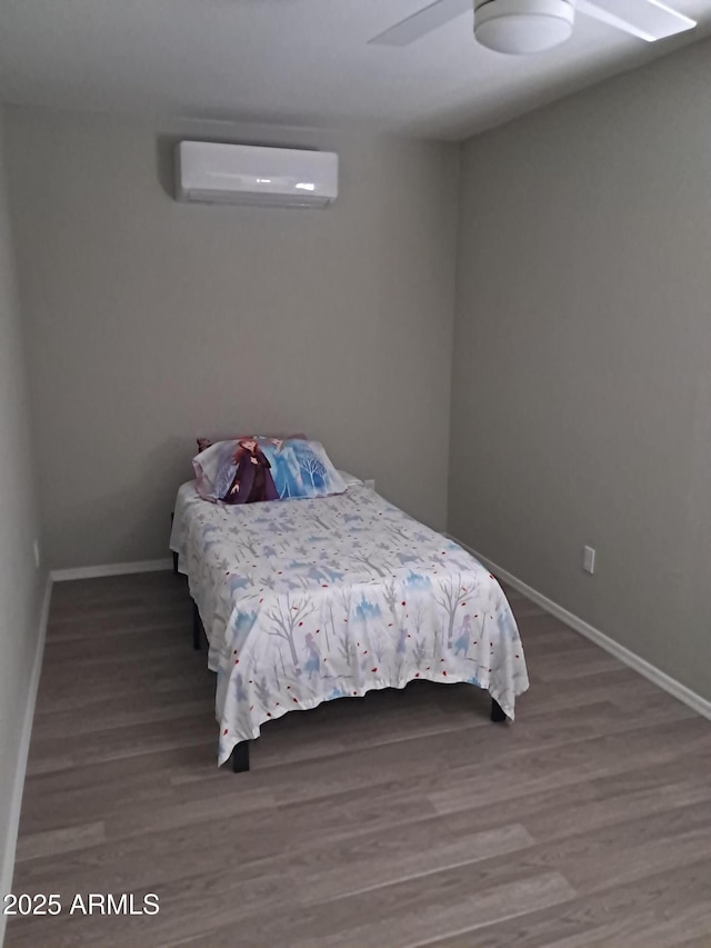 bedroom featuring an AC wall unit, ceiling fan, and hardwood / wood-style floors