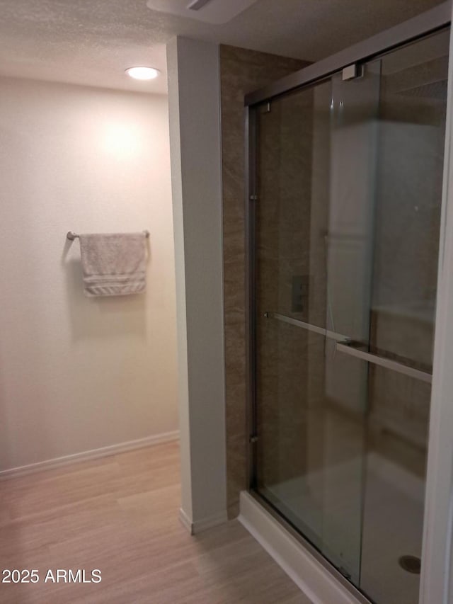 bathroom with wood-type flooring, a textured ceiling, and a shower with door