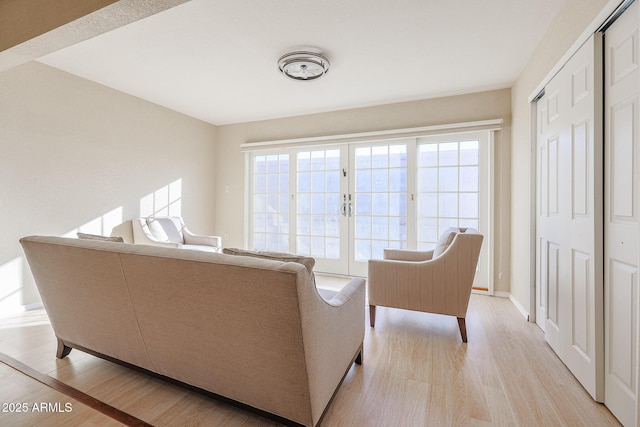 living room featuring french doors, a healthy amount of sunlight, and light hardwood / wood-style flooring