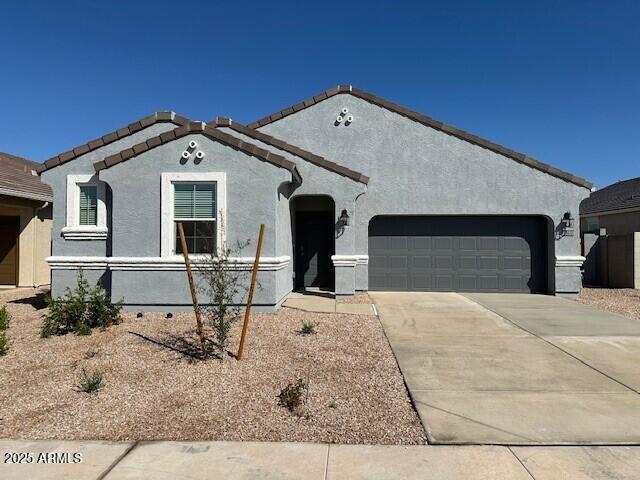 view of front of house with concrete driveway, a tiled roof, an attached garage, and stucco siding