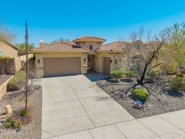 mediterranean / spanish-style home featuring a garage, stucco siding, a tile roof, concrete driveway, and fence