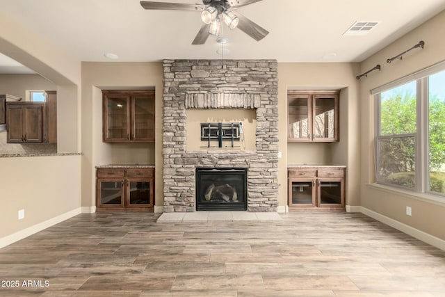 unfurnished living room featuring a fireplace, a ceiling fan, wood finished floors, and baseboards