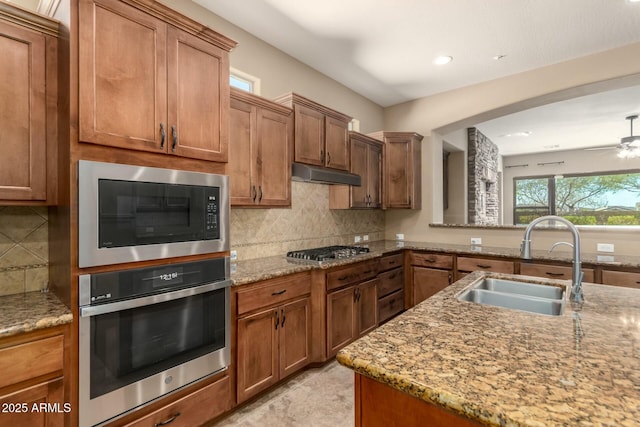 kitchen with appliances with stainless steel finishes, a sink, under cabinet range hood, tasteful backsplash, and recessed lighting