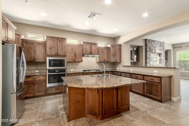kitchen featuring stainless steel appliances, backsplash, light stone countertops, and recessed lighting