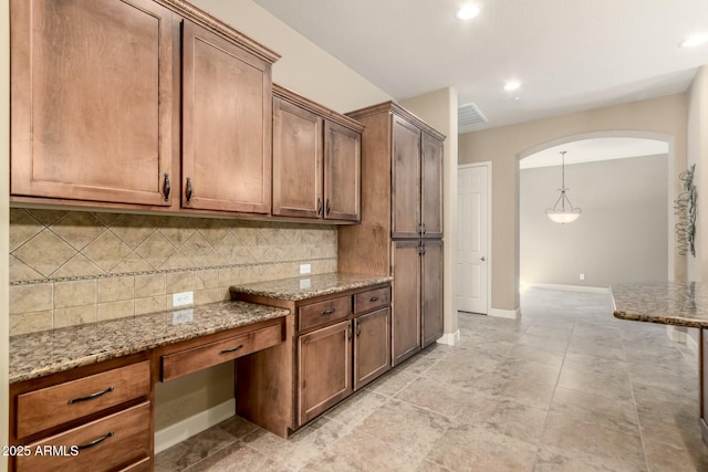 kitchen with arched walkways, backsplash, light stone countertops, baseboards, and recessed lighting