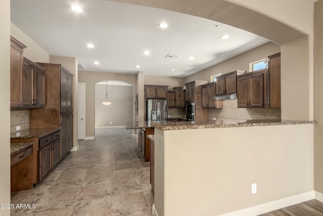 kitchen featuring arched walkways, stainless steel refrigerator with ice dispenser, baseboards, tasteful backsplash, and recessed lighting