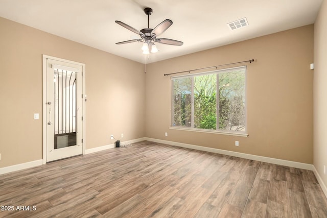 spare room featuring wood finished floors, ceiling fan, and baseboards