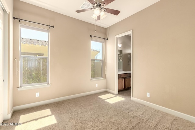 unfurnished bedroom with baseboards, carpet flooring, multiple windows, and ensuite bath