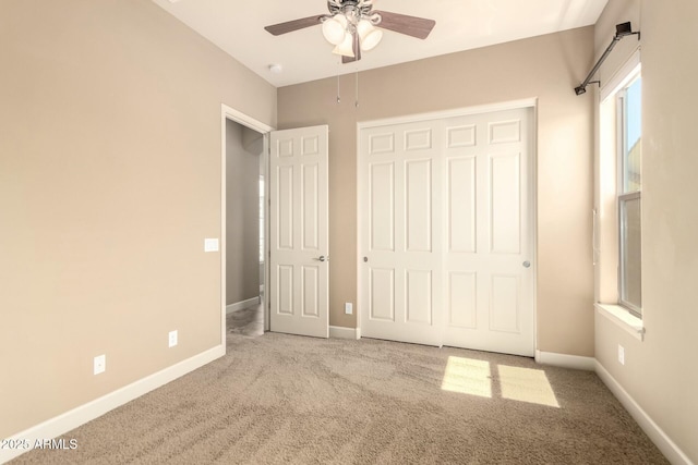 unfurnished bedroom featuring carpet floors, baseboards, a closet, and a ceiling fan