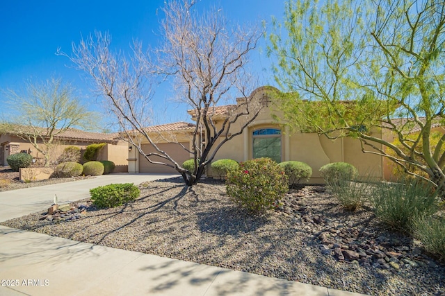 adobe home with concrete driveway, stucco siding, and an attached garage