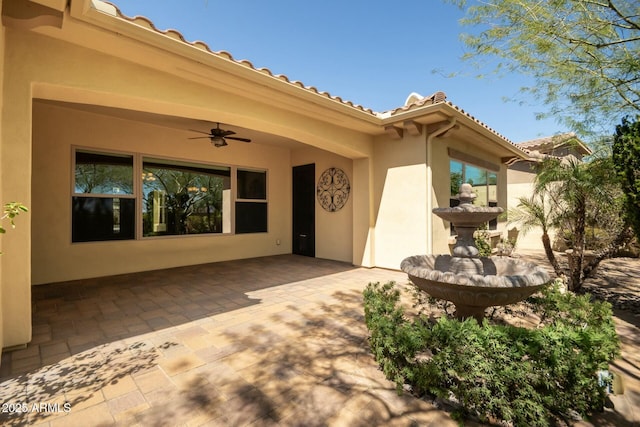 entrance to property featuring a patio, ceiling fan, stucco siding, and a tile roof