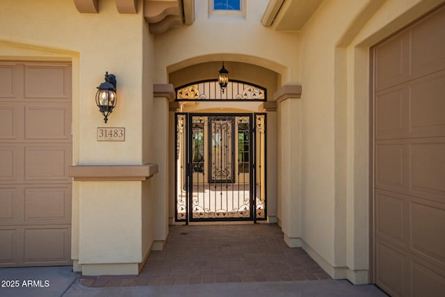 property entrance featuring a garage and stucco siding
