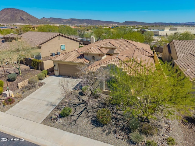 view of front of property featuring a tile roof, stucco siding, an attached garage, driveway, and a mountain view
