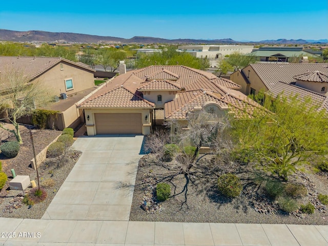 mediterranean / spanish-style home with a garage, stucco siding, and a mountain view