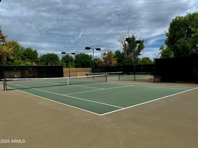 view of tennis court with community basketball court and fence
