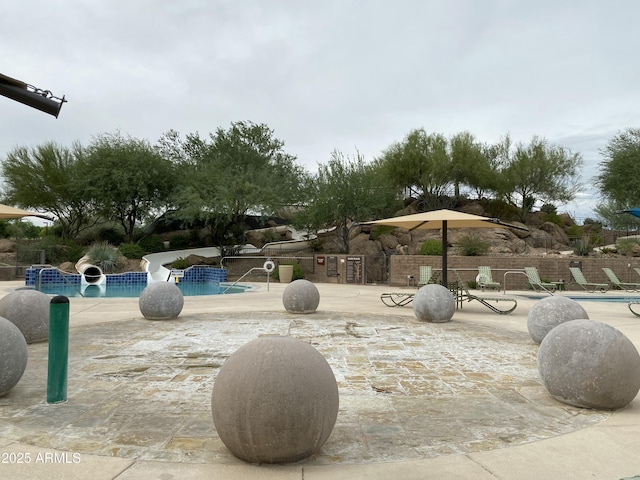 view of property's community featuring a pool, a patio, and fence