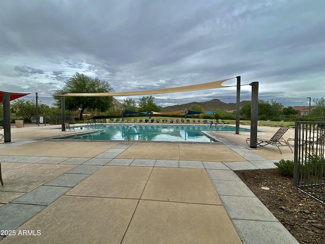 community pool with fence, a patio, and a mountain view