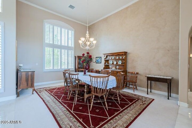 dining area with baseboards, a high ceiling, an inviting chandelier, and ornamental molding