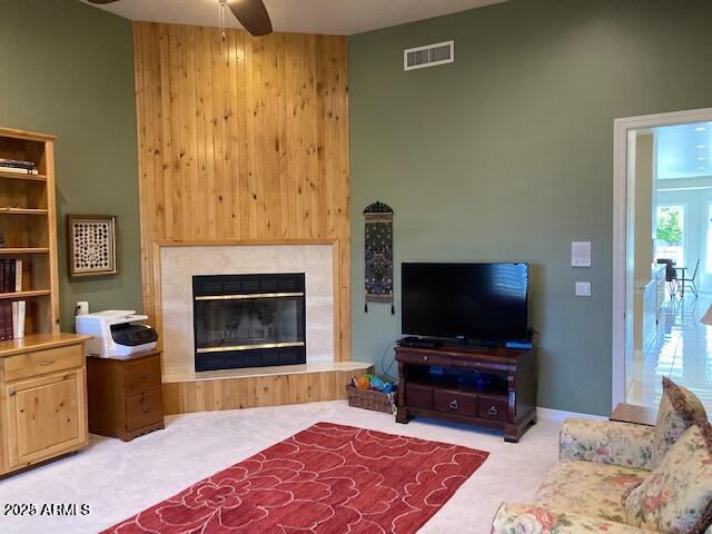 carpeted living area with visible vents, ceiling fan, and a glass covered fireplace