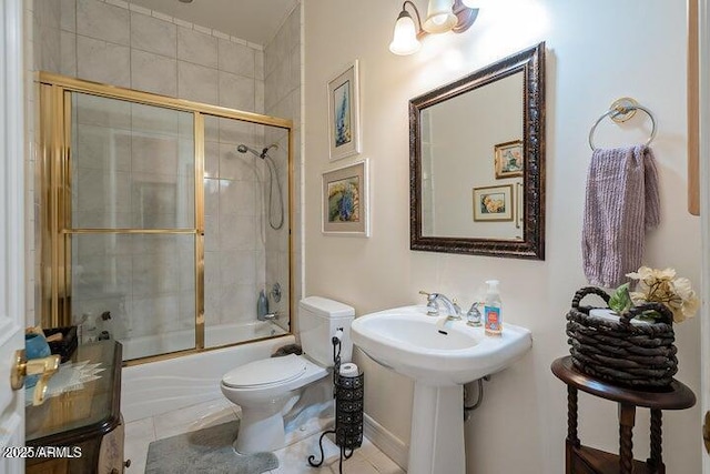 bathroom with a sink, toilet, bath / shower combo with glass door, and tile patterned flooring