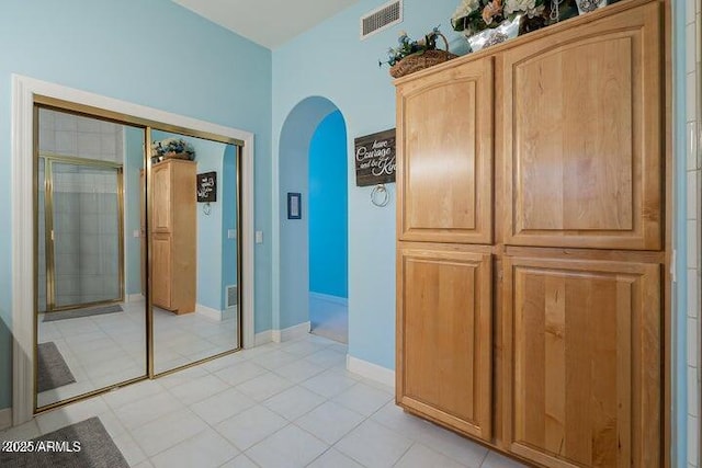 interior space with arched walkways, visible vents, baseboards, and light tile patterned floors