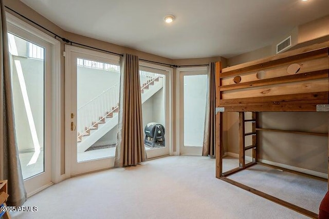 bedroom featuring visible vents, light colored carpet, multiple windows, and access to outside