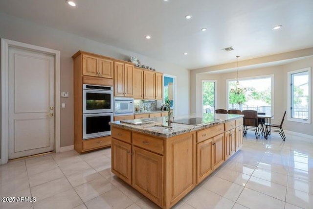 kitchen with double oven, black electric cooktop, light stone countertops, white microwave, and hanging light fixtures