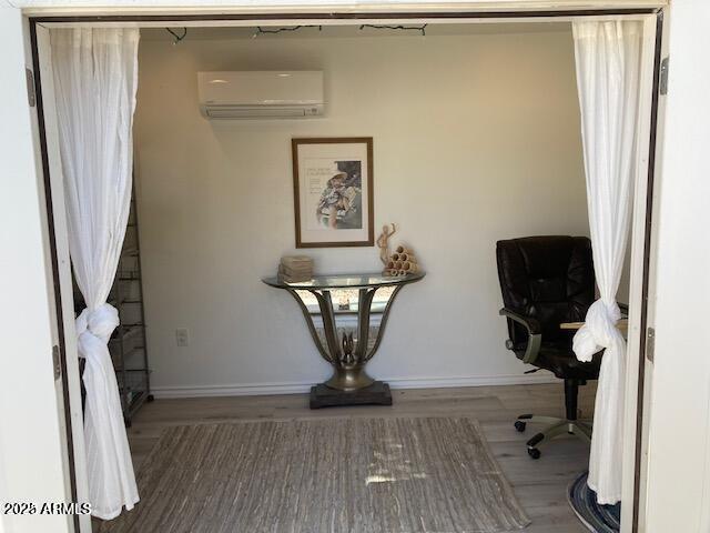 interior space featuring baseboards, an AC wall unit, and wood finished floors