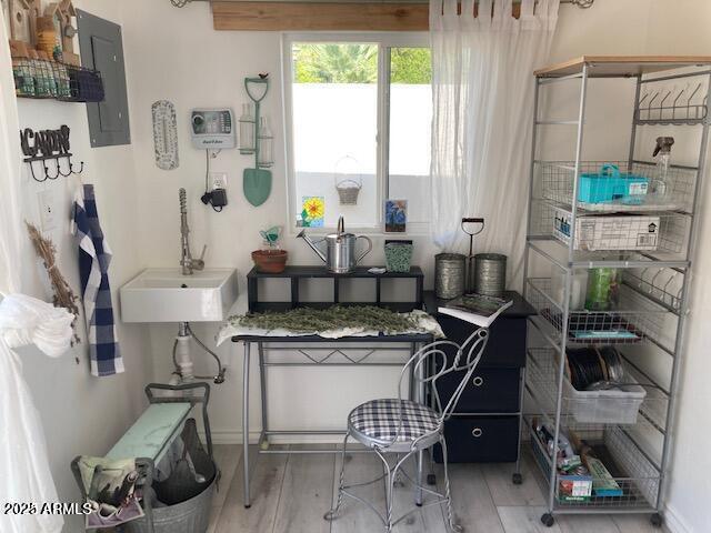 office space featuring electric panel, light wood-type flooring, and a sink