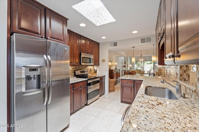 2313 S Grandview Ave, Tempe, AZ 85282 - kitchen featuring stainless steel appliances, a sink, decorative backsplash, a chandelier, and decorative light fixtures