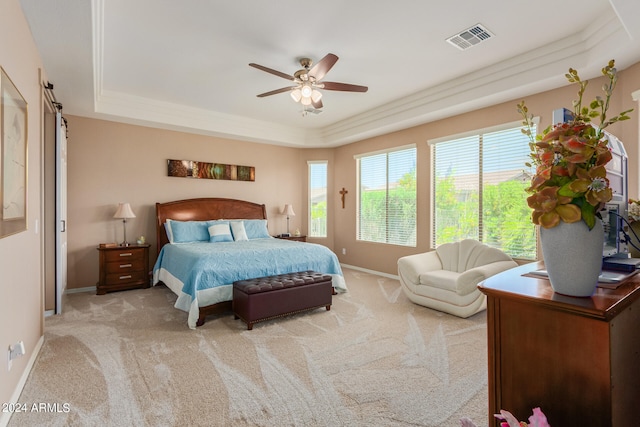 bedroom with a raised ceiling, crown molding, ceiling fan, and light colored carpet