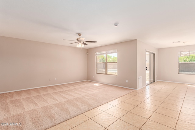 empty room featuring light tile patterned flooring and ceiling fan with notable chandelier