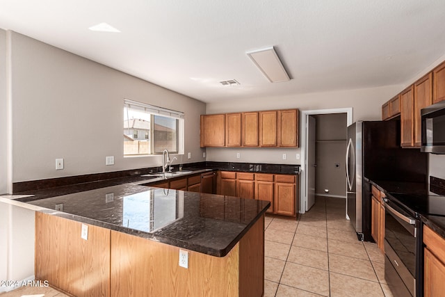 kitchen featuring kitchen peninsula, stainless steel appliances, sink, and dark stone counters