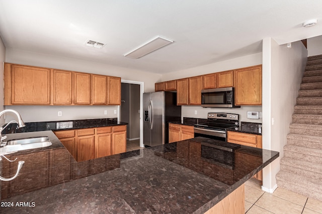 kitchen with sink, appliances with stainless steel finishes, light tile patterned floors, and dark stone counters