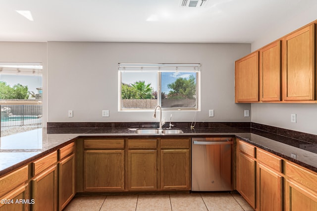 kitchen featuring dark stone counters, light tile patterned floors, sink, and stainless steel dishwasher