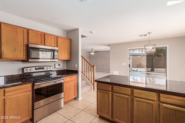 kitchen featuring decorative light fixtures, dark stone countertops, stainless steel appliances, and light tile patterned floors